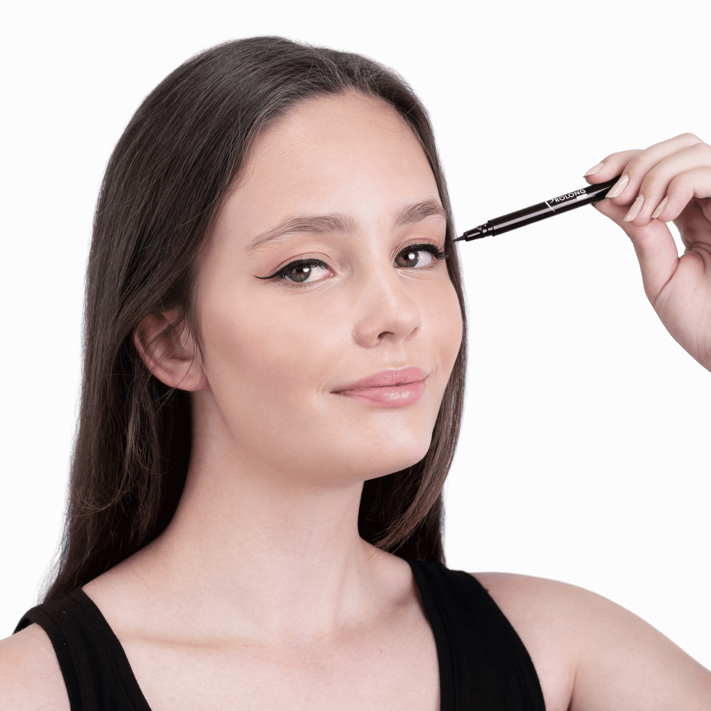 A woman with winged black eyeliner has her hand holding a black eyeliner pen near her eye, shown against a plain white background.