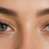 Close-up of a woman’s eyes with soft, natural lash extensions in warm diffused light