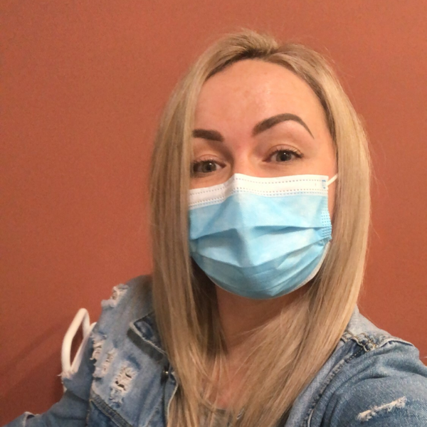 Person wearing a blue surgical mask against a red-brown background