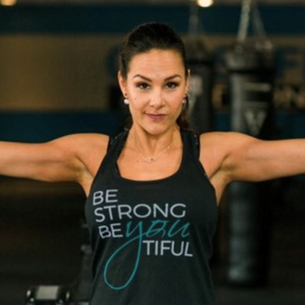 Woman in a gym wearing a tank top with motivational text