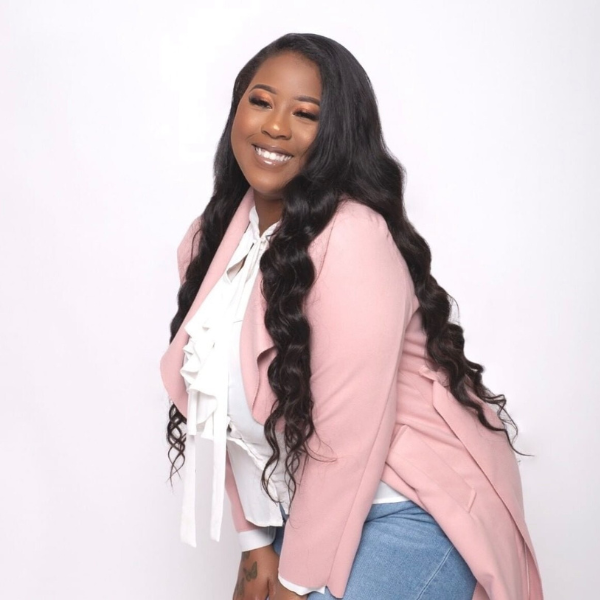 Woman wearing a pink cardigan over a white top with a plain background