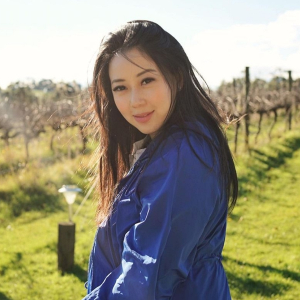 Woman in a blue jacket standing in a vineyard