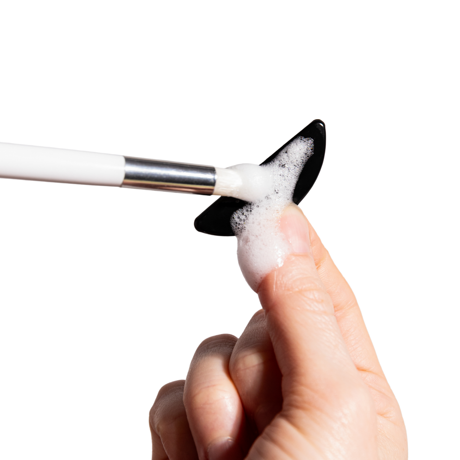 Hand holding a makeup brush washing flutterstop gel pad with flutterstop wash on a white background