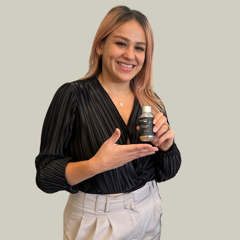 Woman holding a bottle of prolong lash product against a plain background